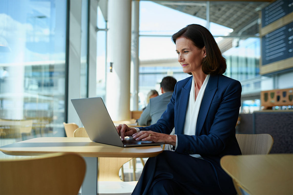 En kvinna sitter vid ett bord med en laptop och arbetar